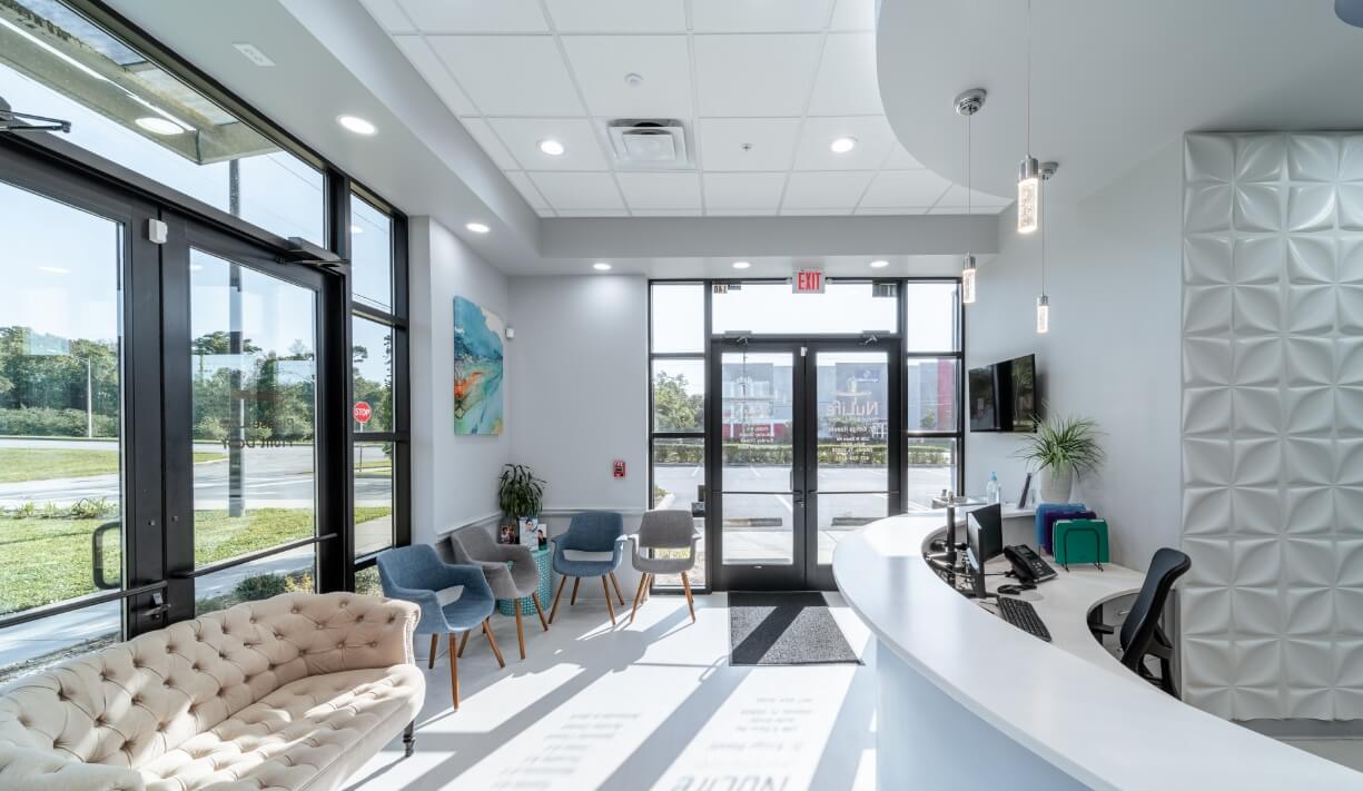 A bright dental reception area with waiting-room seating and a curved front desk