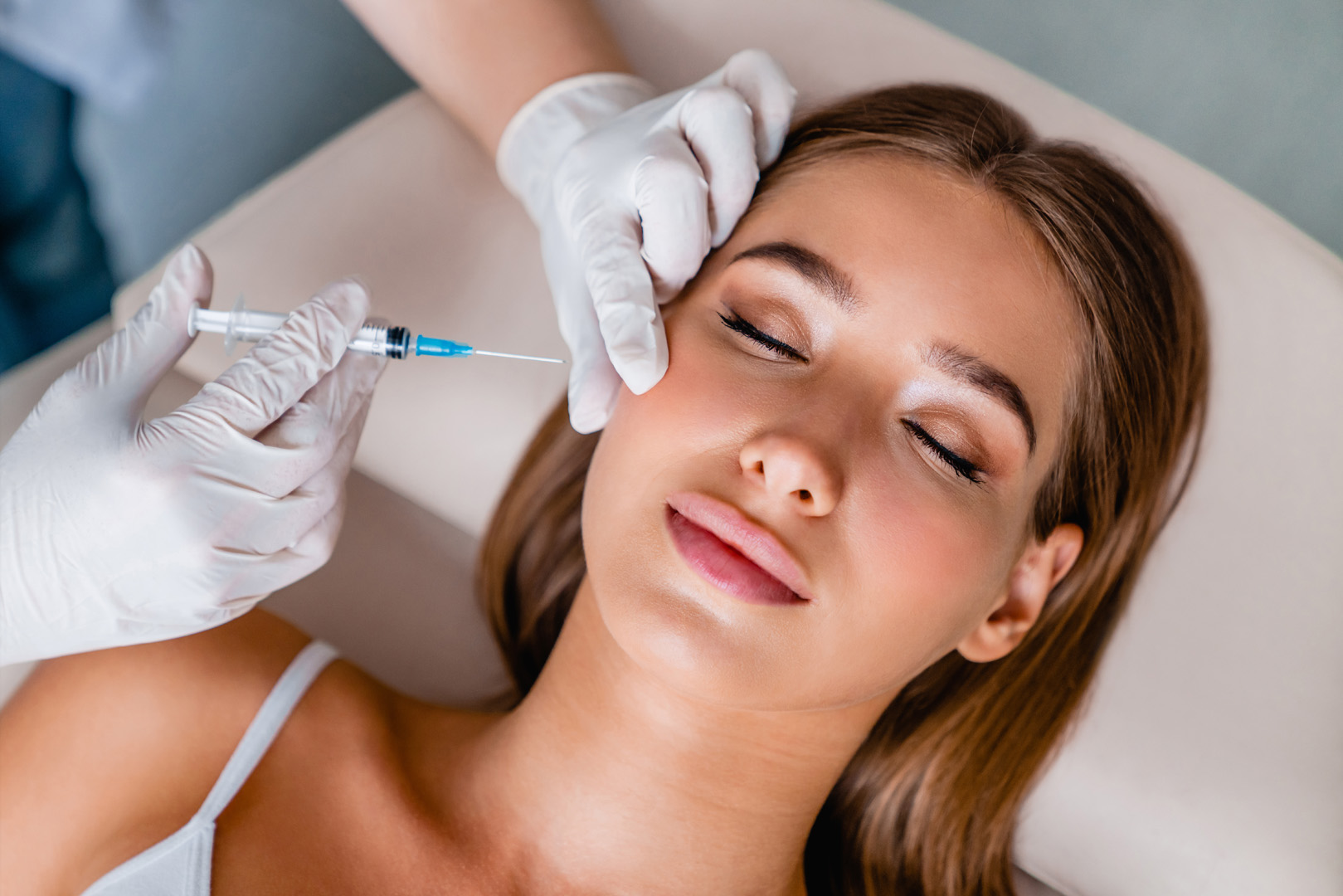 A clinician injecting Botox above a patient's cheekbone