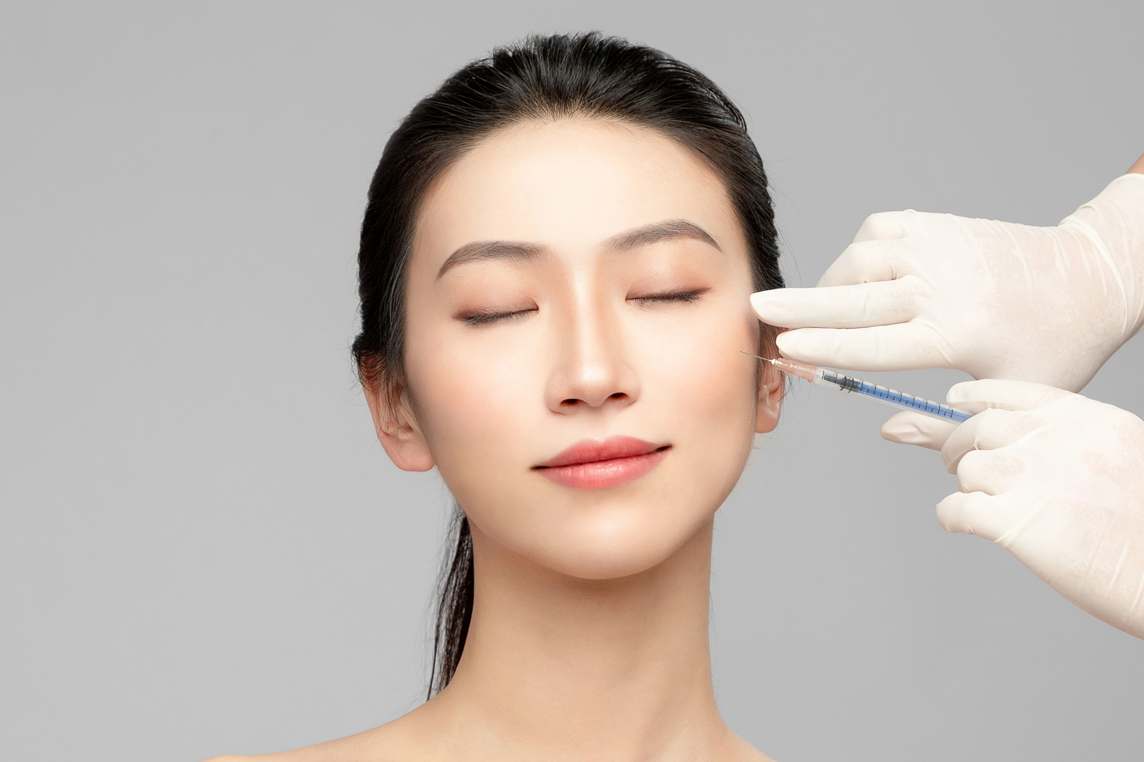 A clinician injecting a cosmetic filler into a patient's cheek