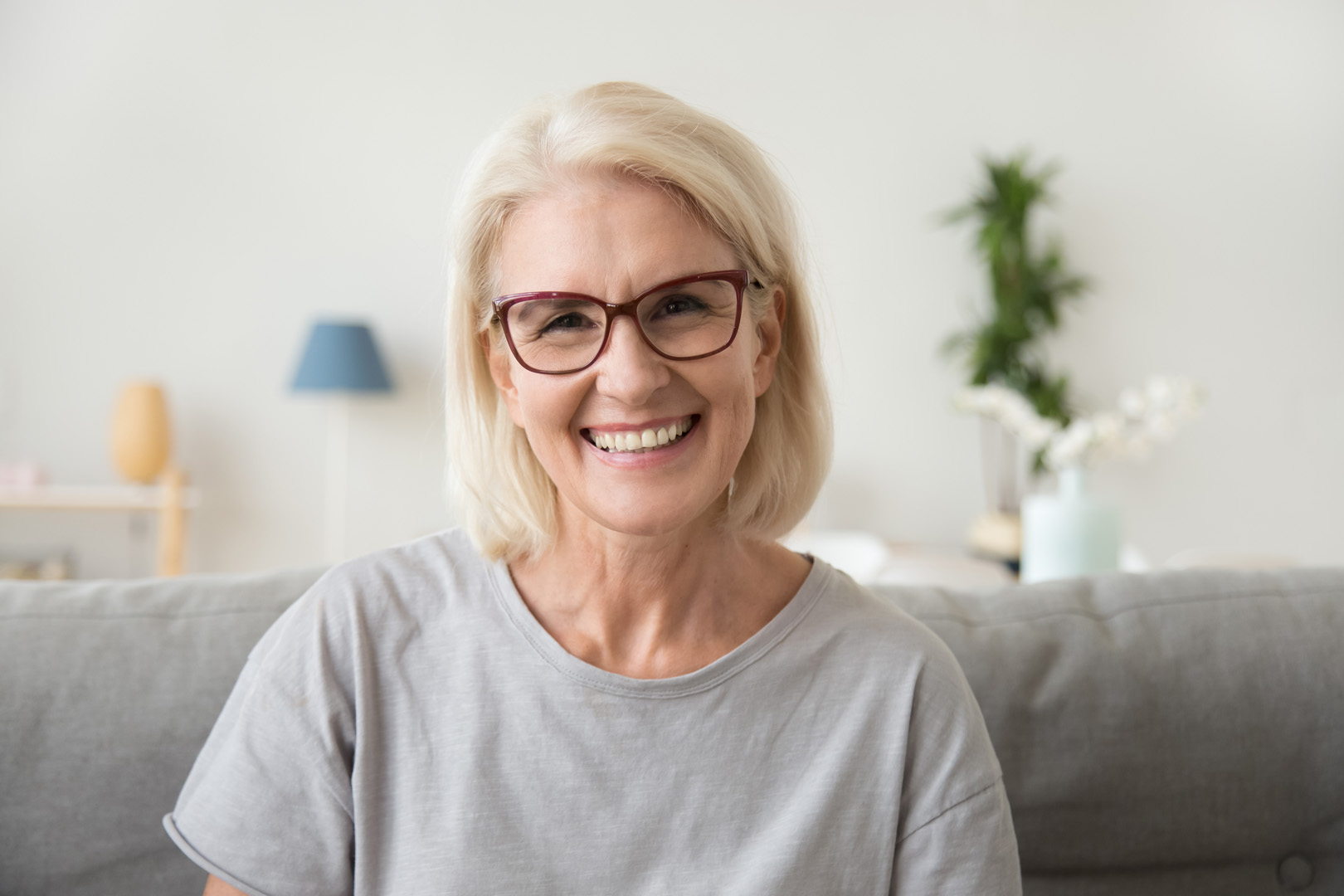 An older woman smiling, seated at home