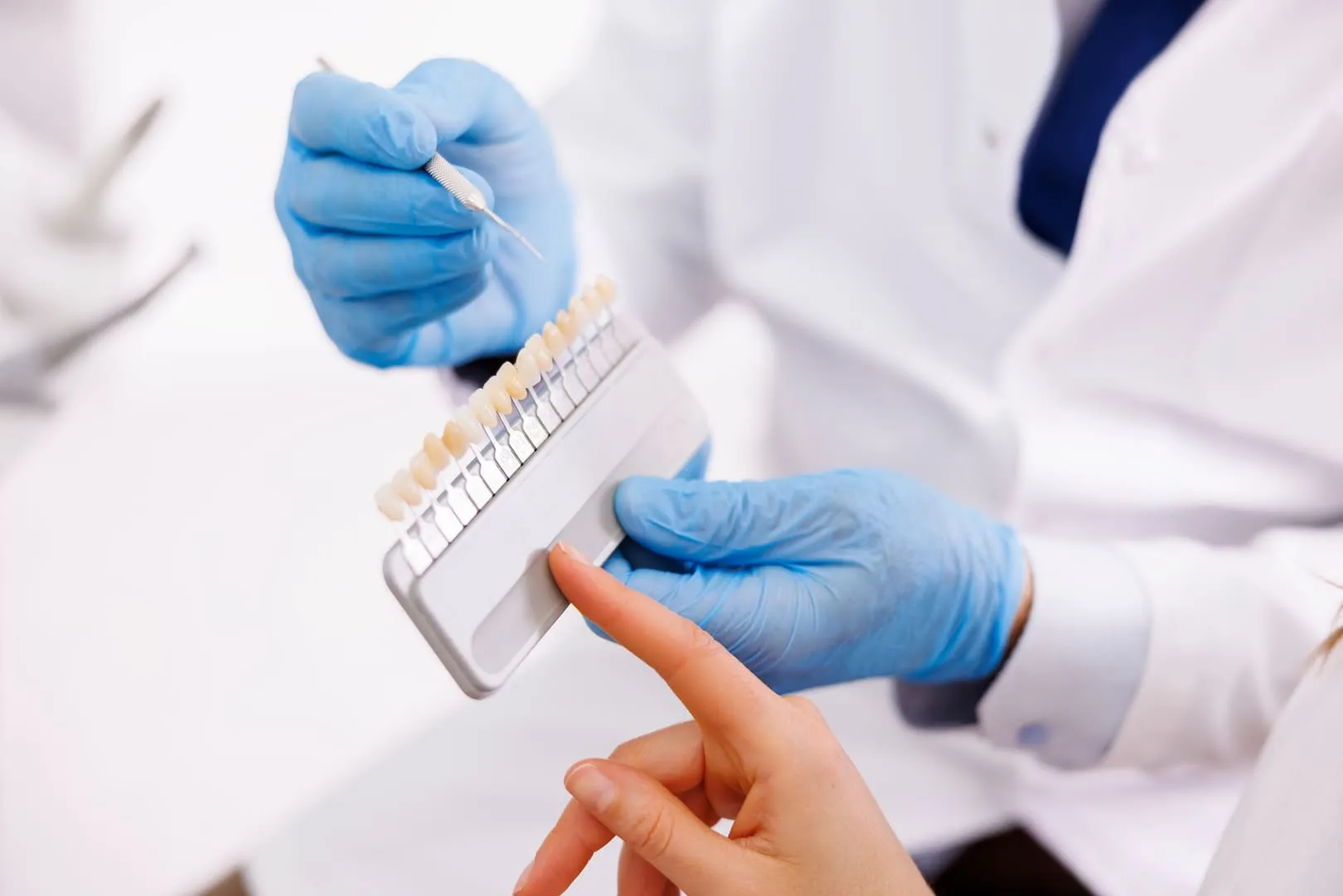 A dentist holding a tooth-shade guide up against a patient's teeth to match the colour