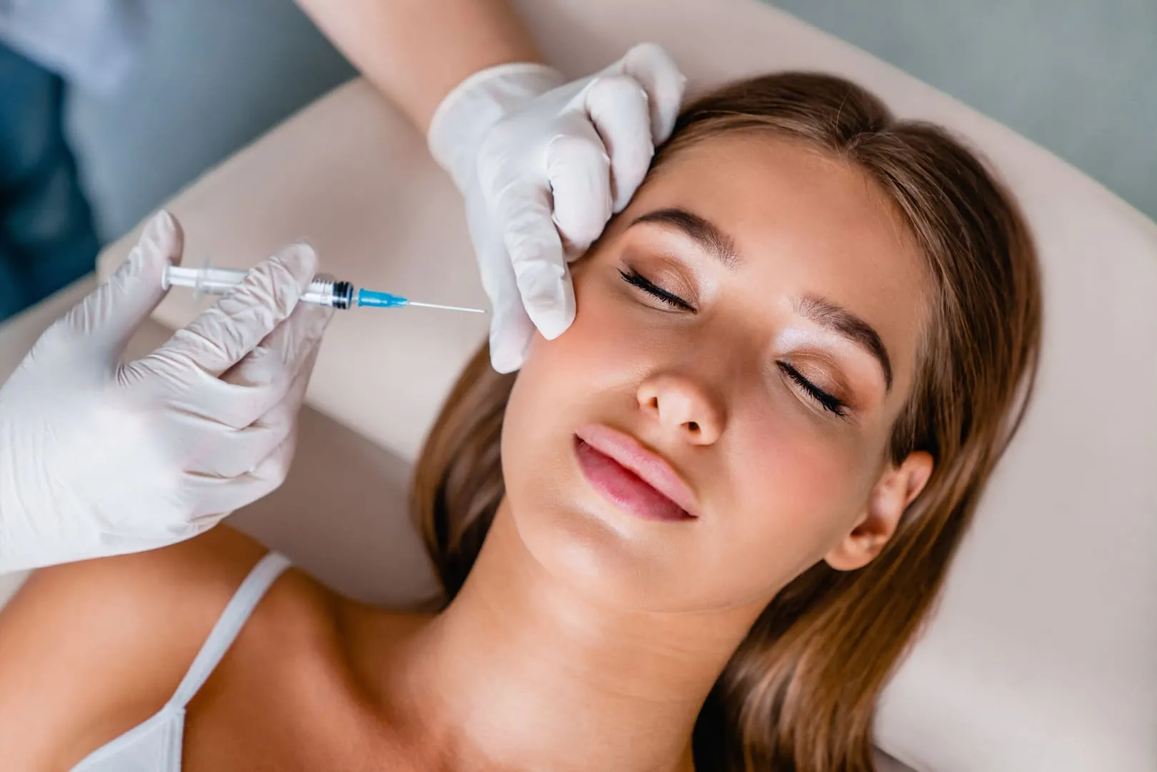 A clinician injecting Botox above a patient's cheekbone