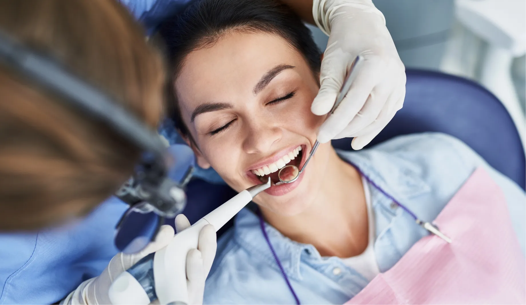 A patient reclining in the dental chair while her teeth are polished