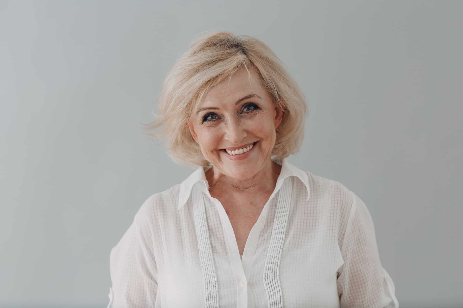 An older woman in a white blouse smiling